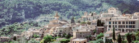 Valldemossas charming stone houses and church spire surrounded by lush mountain greenery.