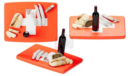 Eine Auswahl an Schweizer Käse, trockener Wurst und frischem Brot, elegant gepaart mit einer Flasche Rotwein, präsentiert auf einer leuchtend orangefarbenen Oberfläche unter dem Motto der Flagge