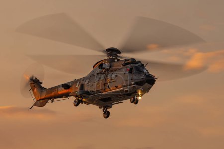Photo for LESZNO, POLAND - JUNE 16, 2023: Swiss Air Force Helicopter Eurocopter AS332 Super Puma fly over Leszno airfield during sunset. - Royalty Free Image