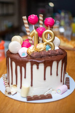 Téléchargez les photos : Gâteau avec une bougie et un ruban rouge avec un glaçage rose et chocolat. - en image libre de droit