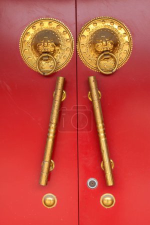 Photo for Closeup of pictures, brass knocker and handle on red door plank - Royalty Free Image