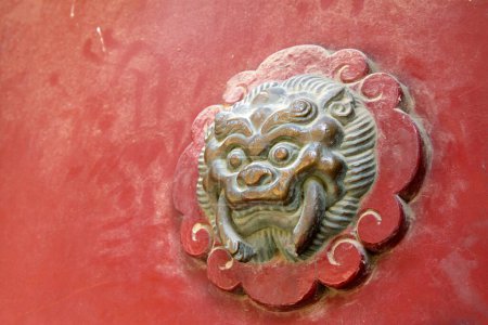 Foto de Beast sculpture on red wooden door in a temple, closeup of photo - Imagen libre de derechos