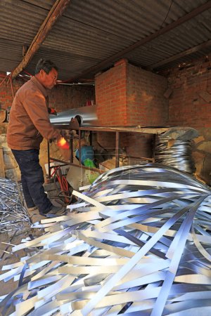 Téléchargez les photos : Luannan County - December 21, 2017: worker Machined metal strip in a handmade workshop, Luannan County, Hebei Province, China. This is the most important traditional handicraft industry in the local area - en image libre de droit