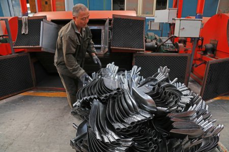 Foto de Condado de Luannan, China - 22 de agosto de 2017: Los trabajadores están ocupados en la línea de producción de palas de acero en una fábrica, Condado de Luannan, provincia de Hebei, China - Imagen libre de derechos