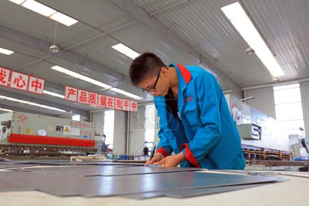 Foto de Condado de Luannan, China - 28 de agosto de 2017: Los trabajadores están ocupados en la línea de producción de placas de acero de esmalte, Condado de Luannan, provincia de Hebei, China - Imagen libre de derechos