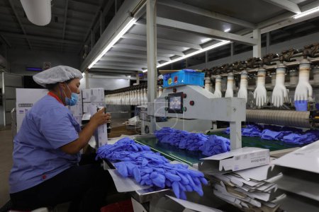 Photo for Luannan County, China - August 28, 2017: Workers are busy on the nitrile-butadiene glove production line, Luannan County, Hebei Province, China - Royalty Free Image