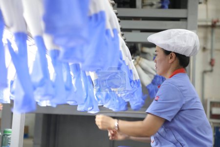 Téléchargez les photos : Comté de Luannan, Chine - 28 août 2017 : Les travailleurs sont occupés sur la ligne de production de gants nitrile-butadiène, comté de Luannan, province du Hebei, Chine - en image libre de droit