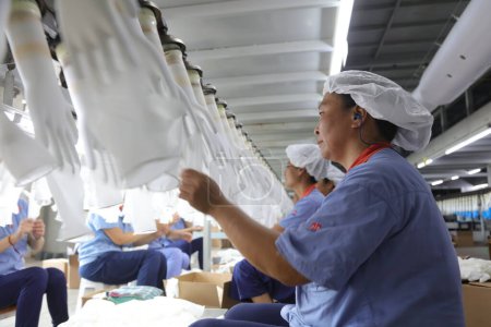 Téléchargez les photos : Comté de Luannan, Chine - 28 août 2017 : Les travailleurs sont occupés sur la ligne de production de gants nitrile-butadiène, comté de Luannan, province du Hebei, Chine - en image libre de droit