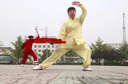 Téléchargez les photos : LUANNAN COUNTY, China - October 15, 2017: Tai Chi Kung Fu Fan Performance in the square, LUANNAN COUNTY, Hebei Province, China - en image libre de droit