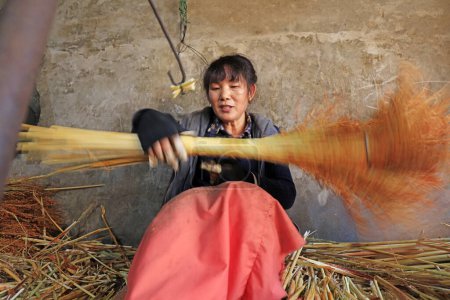 Foto de Luannan County - December 21, 2017: worker processing whisk broom in a hand workshop, Luannan County, Hebei Province, China. This is the most important traditional handicraft industry in the local area - Imagen libre de derechos