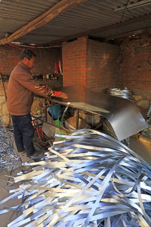 Téléchargez les photos : Luannan County - December 21, 2017: worker Machined metal strip in a handmade workshop, Luannan County, Hebei Province, China. This is the most important traditional handicraft industry in the local area - en image libre de droit