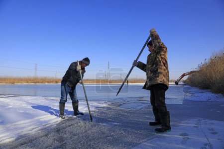 Téléchargez les photos : Comté de Luannan - 23 janvier 2018 : les agriculteurs utilisent un pilon en acier pour séparer la glace dans le champ, Luannan, Hebei, Chin - en image libre de droit