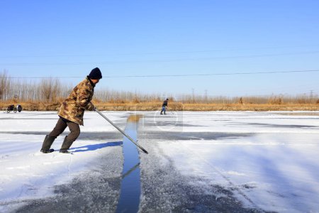 Foto de Condado de Luannan - 23 de enero de 2018: los agricultores utilizan una plaga de acero para separar el hielo en el campo, Luannan, Hebei, Chin - Imagen libre de derechos