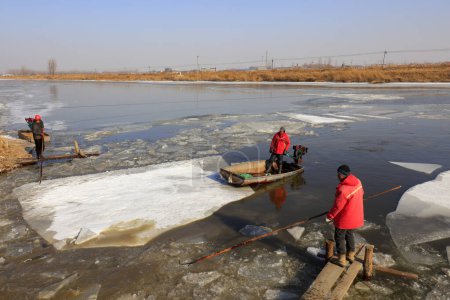 Photo for Luannan County - January 26, 2018: farmers use small boats to drive ice in the wild, Luannan, Hebei, Chin - Royalty Free Image