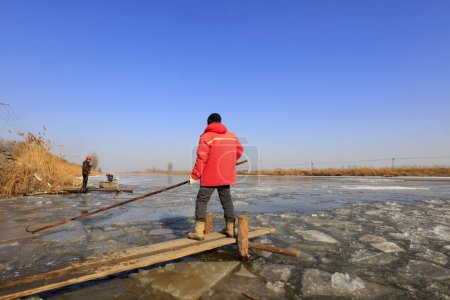 Photo for Luannan County - January 26, 2018: farmers use poles to move ice in the field, Luannan, Hebei, Chin - Royalty Free Image