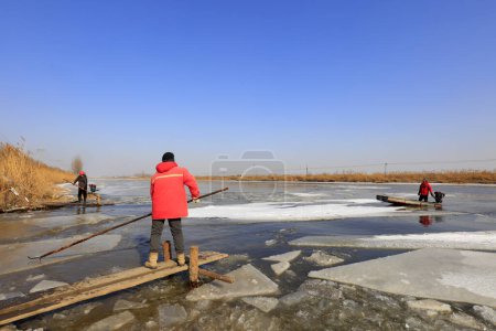Foto de Luannan County - January 26, 2018: farmers use poles to move ice in the field, Luannan, Hebei, Chin - Imagen libre de derechos