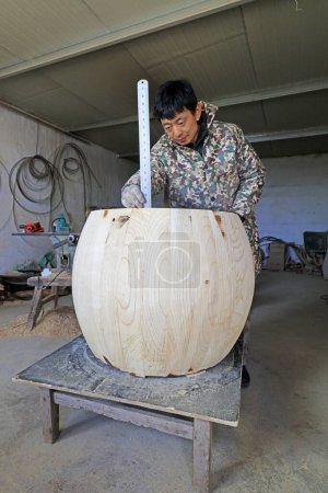 Foto de Luannan County - February 6, 2018: drum craftsman is measuring the height of the drum in workshops, Luannan, Hebei, Chin - Imagen libre de derechos