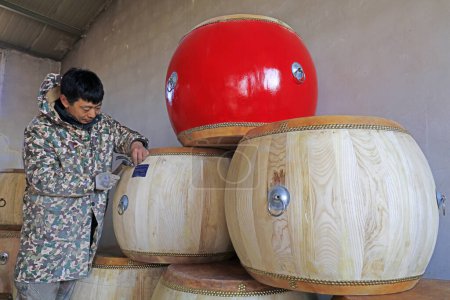 Téléchargez les photos : Luannan County - February 6, 2018: craftsman making the drum fixed the nameplate for the drum in workshops, Luannan, Hebei, Chin - en image libre de droit
