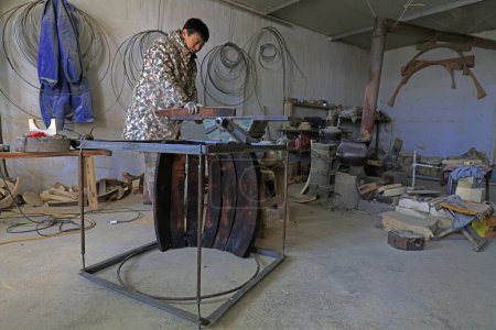 Photo for Luannan County - February 6, 2018: craftsman is working on the side board of the wooden drum in workshops, Luannan, Hebei, Chin - Royalty Free Image