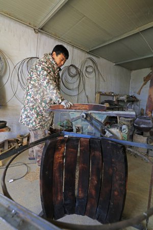 Foto de Luannan County - February 6, 2018: craftsman is working on the side board of the wooden drum in workshops, Luannan, Hebei, Chin - Imagen libre de derechos