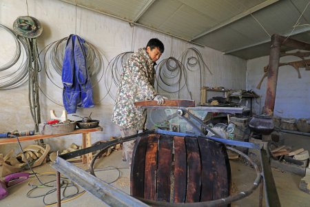 Photo for Luannan County - February 6, 2018: craftsman is working on the side board of the wooden drum in workshops, Luannan, Hebei, Chin - Royalty Free Image