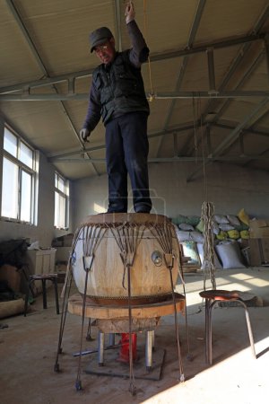 Téléchargez les photos : Luannan County - February 6, 2018: craftsman is treading drumhead in workshops, Luannan, Hebei, Chin - en image libre de droit