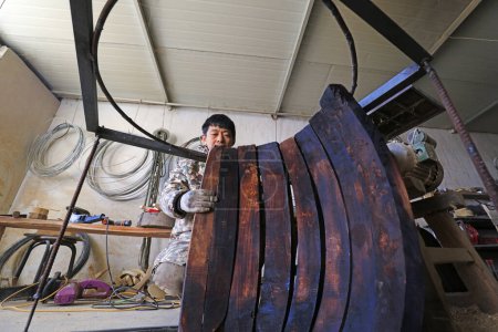 Foto de Luannan County - February 6, 2018: craftsman is working on the side board of the wooden drum in workshops, Luannan, Hebei, Chin - Imagen libre de derechos