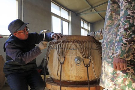 Photo for Luannan County - February 6, 2018: craftsman is working on the drum in workshops, Luannan, Hebei, Chin - Royalty Free Image