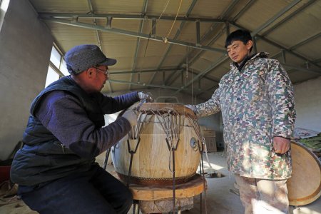 Foto de Luannan County - February 6, 2018: craftsman is working on the drum in workshops, Luannan, Hebei, Chin - Imagen libre de derechos