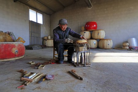 Photo for Luannan County - February 6, 2018: craftsman is working on the drum in workshops, Luannan, Hebei, Chin - Royalty Free Image