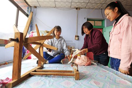 Photo for Luannan County, March 30, 2018: Indigenous weaving technology inheriting people, guiding students to use spinning workers, Luannan County, Hebei Province, China - Royalty Free Image