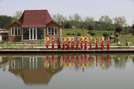 Photo for Luannan County - May 18, 2018: ladies in cheongsam are beside the pond, Luannan County, Hebei Province, China - Royalty Free Image