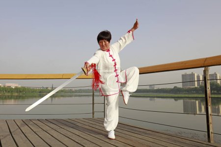 Photo for LUANNAN COUNTY, China - May 27, 2018: A woman is practicing Tai Chi Sword in the park, LUANNAN COUNTY, Hebei Province, Chin - Royalty Free Image