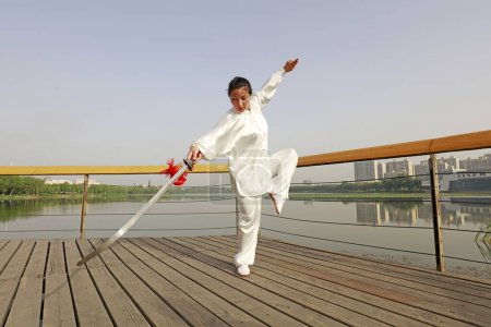Foto de CONDADO DE LUANNAN, China - 27 de mayo de 2018: Una mujer está practicando la espada Tai Chi en el parque, CONDADO DE LUANNAN, Provincia de Hebei, Chin - Imagen libre de derechos