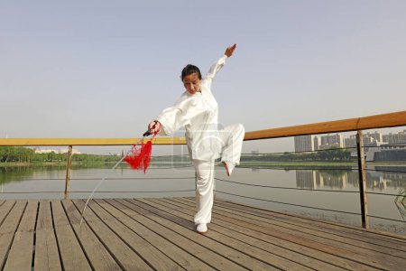 Photo for LUANNAN COUNTY, China - May 27, 2018: A woman is practicing Tai Chi Sword in the park, LUANNAN COUNTY, Hebei Province, Chin - Royalty Free Image