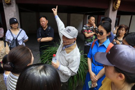 Foto de Shanghai, China - 2 de junio de 2018: Un instructor de edad avanzada explica a los turistas en Yu Garden, Shanghai, China - Imagen libre de derechos