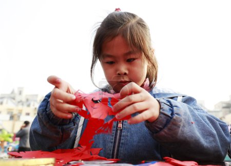 Téléchargez les photos : Comté de Luannan - 14 octobre 2018 : Petite fille apprenant l'art traditionnel chinois découpé sur papier, comté de Luannan, province du Hebei, Chin - en image libre de droit