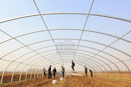Photo for Luannan county - March 22, 2018: workers are building an oval tube full steel greenhouse greenhouse, luannan county, hebei province, China - Royalty Free Image