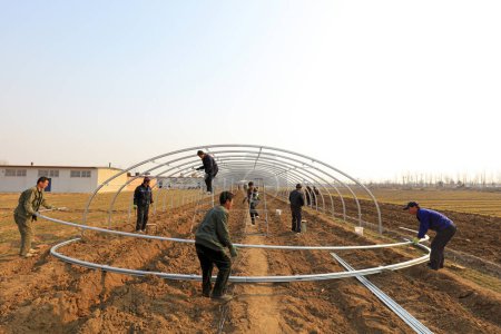 Foto de Condado de Luannan - 22 de marzo de 2018: los trabajadores están construyendo un invernadero de acero de tubo oval completo, condado de Luannan, provincia de Hebei, China - Imagen libre de derechos