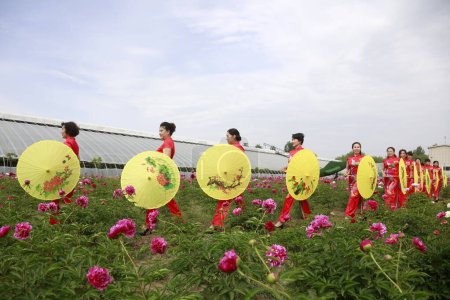 Foto de Condado de Luannan - 18 de mayo de 2018: Señora vestida de rojo en el jardín, Condado de Luannan, provincia de Hebei, China - Imagen libre de derechos