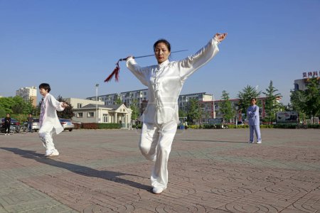 Photo for Luannan County - May 19, 2018: A lady is practicing tai chi sword in the park, Luannan County, Hebei Province, Chin - Royalty Free Image
