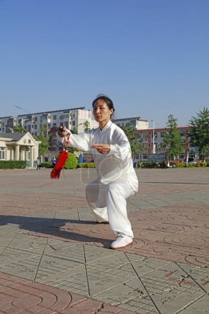 Foto de Condado de Luannan - 19 de mayo de 2018: Una dama está practicando la espada tai chi en el parque, Condado de Luannan, provincia de Hebei, Chin - Imagen libre de derechos