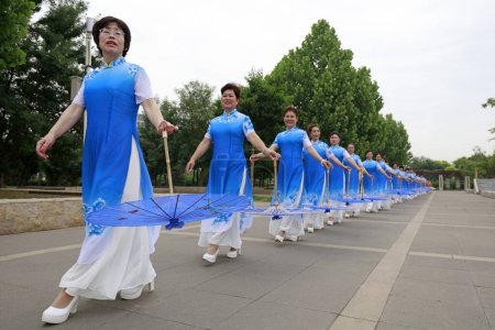 Foto de CONDADO DE LUANNAN, China - 9 de junio de 2018: Mujeres en cheongsam actúan en el parque, condado de LUANNAN, provincia de Hebei, China - Imagen libre de derechos