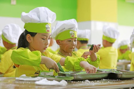 Téléchargez les photos : COMTÉ DE LUANNAN, Chine - 14 juin 2018 : Les enfants de la maternelle apprennent à faire des zongzi, COMTÉ DE LUANNAN, province du Hebei, Chine - en image libre de droit