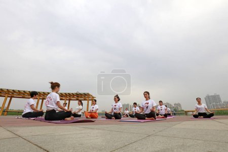 Foto de CONDADO DE LUANNAN, China - 23 de junio de 2018: Las mujeres practican yoga al aire libre en un parque, CONDADO DE LUANNAN, provincia de Hebei, China - Imagen libre de derechos