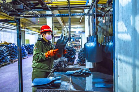 Foto de LUANNAN COUNTY, provincia de Hebei, China - 15 de abril de 2019: Los trabajadores están ocupados en la línea de producción en una planta de producción de palas de acero. - Imagen libre de derechos