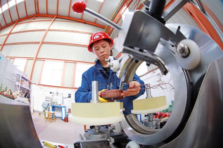 Foto de LUANNAN COUNTY, provincia de Hebei, China - 15 de abril de 2019: Trabajadoras en la operación de la máquina de bobinado CNC en el taller. - Imagen libre de derechos