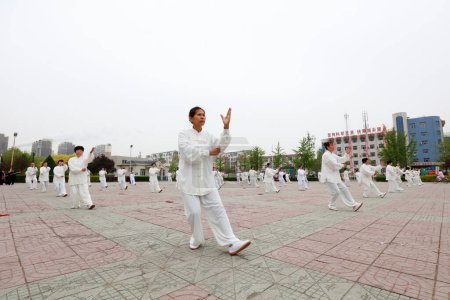 Foto de CONDADO DE LUANNAN, provincia de Hebei, China - 29 de abril de 2019: la gente practica Taijiquan en la plaza del parque. - Imagen libre de derechos