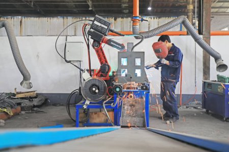 Photo for Luannan County, China - June 21, 2019: Workers inspect the work of intelligent welding robots in a factory, Luannan County, Hebei Province, China. At present, many Chinese enterprises use intelligent robots to work. - Royalty Free Image