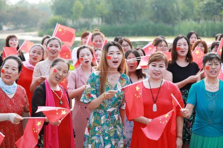 Foto de Condado de Luannan, China - 5 de julio de 2019: La gente ondeó banderas y cantó canciones patrióticas en el parque, Condado de Luannan, provincia de Hebei, China. - Imagen libre de derechos
